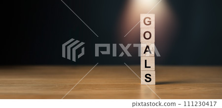 Wooden blocks stacked vertically spelling GOALS with spotlight effect, symbolizing focus on setting personal and business objectives. 111230417