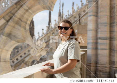 Beautiful 30s woman in sunglasses posing on Roof of Milan Cathedral Duomo di Milano, Italy. Traveling Europe in summer. Attractive female is exploring city. Top tourist attraction Beautiful 30s woman in sunglasses posing on Roof of Milan Cathedral Duomo di Milano, Italy. Traveling Europe in summer. Attractive female is exploring city. Top tourist attraction 111230743