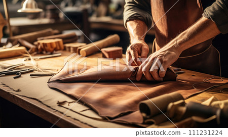 Artisan craftsman works leather, skillfully creating in his workshop. Artisan craftsman works leather, skillfully creating in his workshop. 111231224