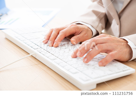一位身穿西裝的中年婦女的手在帶著電腦的辦公桌前工作 111231756
