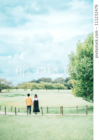 Couple walking in a park with blue sky and greenery Couple walking in a park with blue sky and greenery 111232476