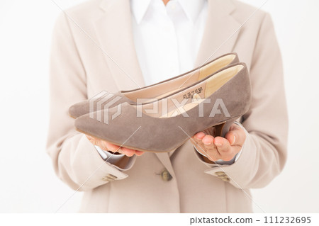 Middle-aged business woman in a suit holding pumps 111232695
