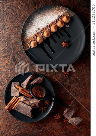 Chocolate truffles on a black plate with chocolate sauce. Chocolate truffles on a black plate with chocolate sauce. 111232709