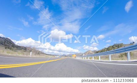 Vehicle is cruising along the Cuyama Highway under the bright sun. The surrounding landscape is illuminated by the radiant sunshine, creating a picturesque and inviting scene as the car travels Vehicle is cruising along the Cuyama Highway under the bright sun. The surrounding landscape is illuminated by the radiant sunshine, creating a picturesque and inviting scene as the car travels 111233068