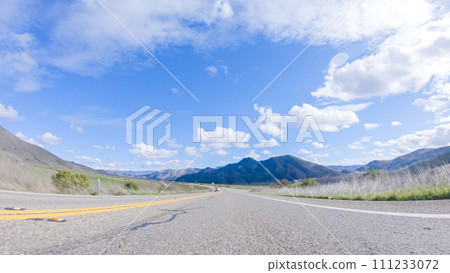 Vehicle is cruising along the Cuyama Highway under the bright sun. The surrounding landscape is illuminated by the radiant sunshine, creating a picturesque and inviting scene as the car travels Vehicle is cruising along the Cuyama Highway under the bright sun. The surrounding landscape is illuminated by the radiant sunshine, creating a picturesque and inviting scene as the car travels 111233072