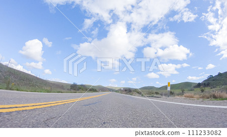 On a clear winter day, a car smoothly travels along Highway 101 near Santa Maria, California, under a brilliant blue sky, surrounded by a blend of greenery and golden hues. On a clear winter day, a car smoothly travels along Highway 101 near Santa Maria, California, under a brilliant blue sky, surrounded by a blend of greenery and golden hues. 111233082