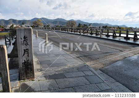 Kyoto in spring in Japan, the streets around Arashiyama, tourist attraction Togetsukyo Bridge and wooden signboards, beautiful cherry blossoms and fresh greenery Kyoto in spring in Japan, the streets around Arashiyama, tourist attraction Togetsukyo Bridge and wooden signboards, beautiful cherry blossoms and fresh greenery 111233386