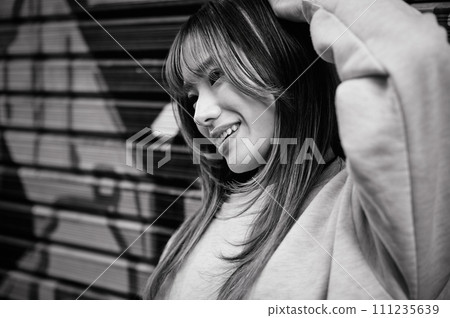 一名年輕女子站在百葉窗前,百葉窗上畫著塗鴉 一名年輕女子站在百葉窗前,百葉窗上畫著塗鴉 111235639
