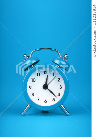 Close up one blue alarm clock over blue background 111235914