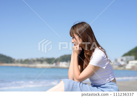 A woman standing on a sandy beach on a sunny day A woman standing on a sandy beach on a sunny day 111236337