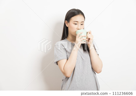 Asian woman with a cup of coffee in her hand on white Asian woman with a cup of coffee in her hand on white 111236606