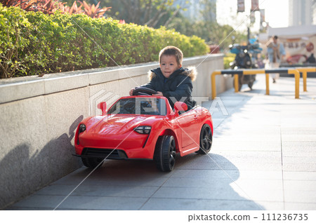Adventurous Toddler Drives Red Sports Car with Joyful Glee 111236735