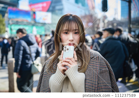 A young woman in winter clothes with a smartphone (Shibuya) A young woman in winter clothes with a smartphone (Shibuya) 111237589