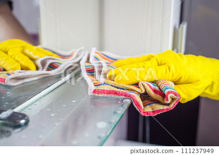 Maid with rubber glove cleaning tap and sink. Maid with rubber glove cleaning tap and sink. 111237949