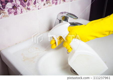 Maid with rubber glove cleaning tap and sink. Maid with rubber glove cleaning tap and sink. 111237961