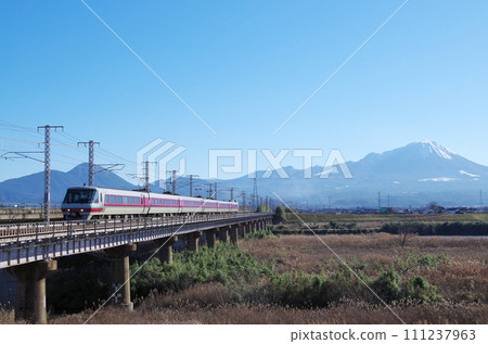 The 381-series limited express Yakumo, a panoramic formation with a standard, relaxed, yellow color, runs over the long railway bridge of the Hino River with Mt. Daisen in the background. 111237963