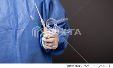 A female doctor is a gynecologist in a blue robe. Gynecological accessories, venus mirror, brush. Grey background, empty space for text. 111238021