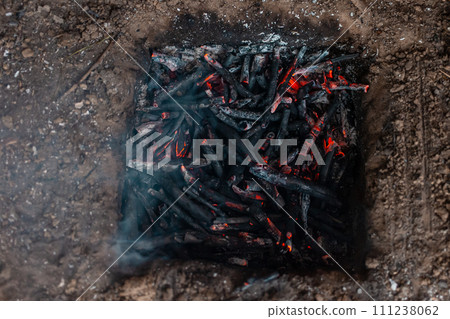 Coals from a campfire in a sand pit. 111238062
