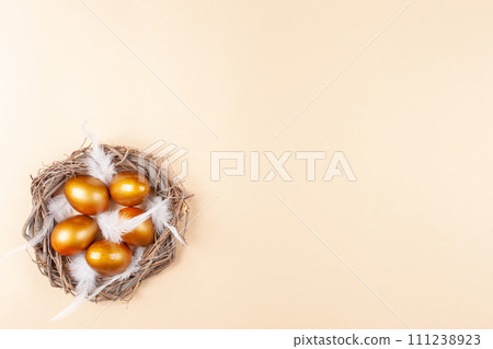 Empty space for text, a banner of happy Easter. Painted golden eggs, white feathers. copy space flat lay top view Nest 111238923