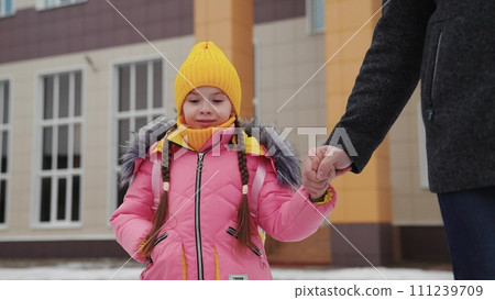 girl holding her father hand, school road education classes, concept happy family, little child kid daughter with school backpack walking through snow boots, school student with backpack, daughter bag 111239709