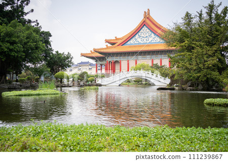 Beautiful Asian garden with bonsais, pond with bridge and majestic temple in background, wide,Taiwan 111239867