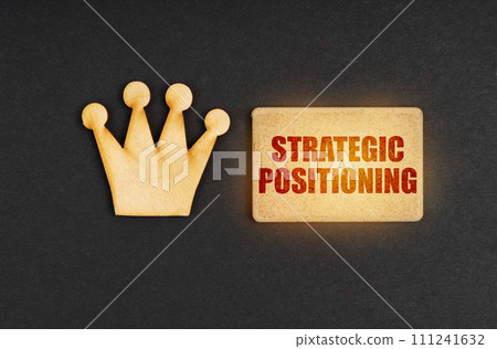 On a black background there is a wooden crown of the leader and a sign with the inscription - Strategic Positioning On a black background there is a wooden crown of the leader and a sign with the inscription - Strategic Positioning 111241632