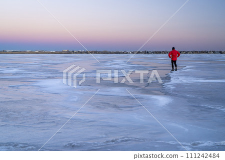 lonely male figure on a frozen lake at dusk in Colorado - Boyd Lake State Park 111242484