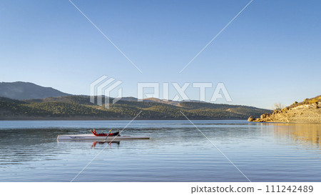 male rower is resting in his rowing shell on Carter Lake in fall or winter scenery in northern Colorado 111242489