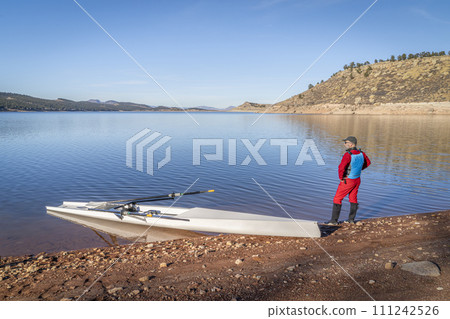 Senior male rower and a coastal rowing shell is landing on a rocky shore of Carter Lake in fall or winter scenery in northern Colorado. Senior male rower and a coastal rowing shell is landing on a rocky shore of Carter Lake in fall or winter scenery in northern Colorado. 111242526