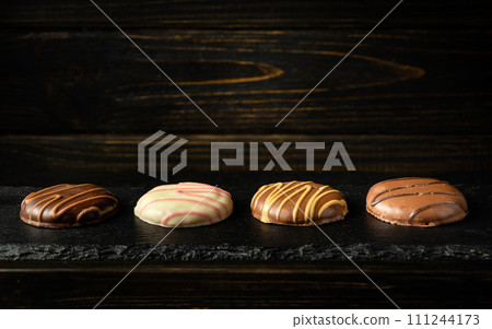 Chocolate cookies or chocolate brownie on a black serving board. Delicious dessert concept for a hotel. Millionaires shortbread idea. Advertising space 111244173