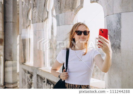 Beautiful woman taking selfie on Roof of Milan Cathedral Duomo di Milano, Italy. Traveling Europe in summer. Attractive female is exploring city, tourist makes photo or video on smartphone Beautiful woman taking selfie on Roof of Milan Cathedral Duomo di Milano, Italy. Traveling Europe in summer. Attractive female is exploring city, tourist makes photo or video on smartphone 111244288
