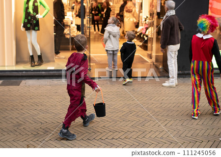 The kids dressed up in the city on Halloween asking for candy in a shop 111245056