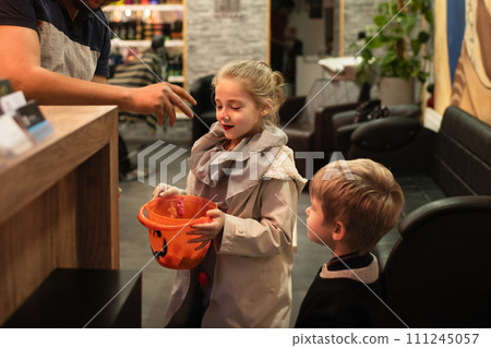 A man puts candy in a pumpkin-shaped bucket for Halloween. 111245057