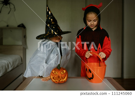 Children dressed as ghosts perform magic at home on Halloween 111245060