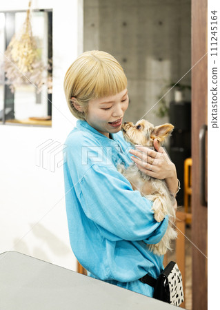 Short-haired woman holding a Yorkshire terrier at a dog salon Short-haired woman holding a Yorkshire terrier at a dog salon 111245164