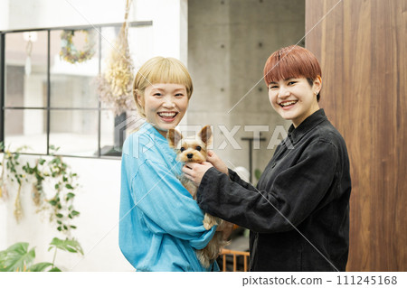Female staff holding a Yorkshire terrier at a dog salon Female staff holding a Yorkshire terrier at a dog salon 111245168
