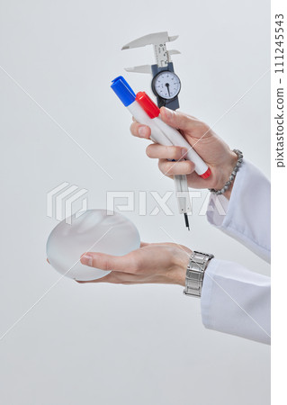 plastic surgeon holding a silicone breast implant in his hand close up, mastopexy concept, BREAST LIFT 111245543