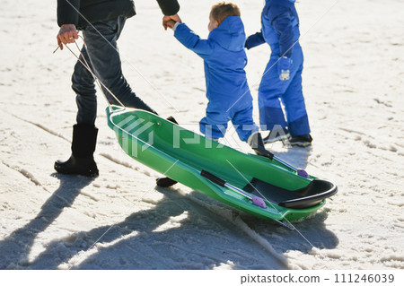 A father with children sledding in the snow 111246039