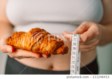 Person's hand holding green apple with grey measurement tape isolated on white background. Weight loss and dieting concept. Person's hand holding green apple with grey measurement tape isolated on white background. Weight loss and dieting concept. 111246413