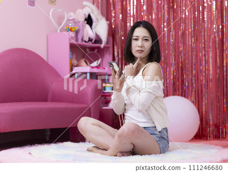 Young woman looking at her smartphone in her room 111246680