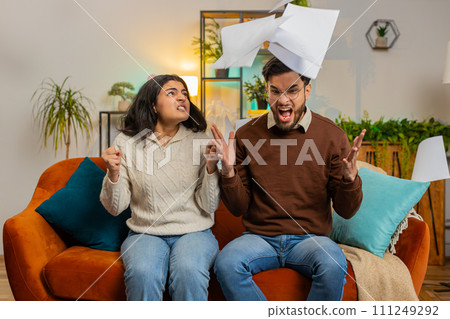 Stressed Indian family looking at unpaid bank debt bills doing paperwork throws home paper bills Stressed Indian family looking at unpaid bank debt bills doing paperwork throws home paper bills 111249292