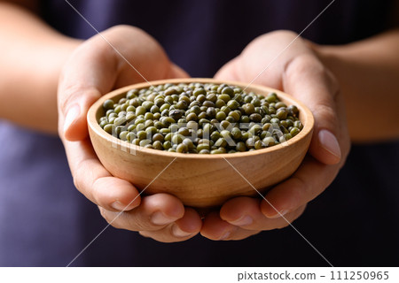 Green mung bean in wooden bowl holding by hand, Food ingredients 111250965