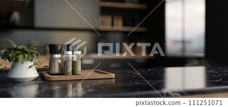 A set of spice bottles on a luxury black marble kitchen countertop in a modern black kitchen. A set of spice bottles on a luxury black marble kitchen countertop in a modern black kitchen. 111251071
