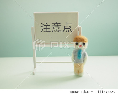 A man made of wool felt with caution letters on a whiteboard A man made of wool felt with caution letters on a whiteboard 111252829