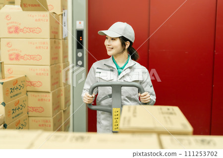 A female worker moves inventory using a jack 111253702