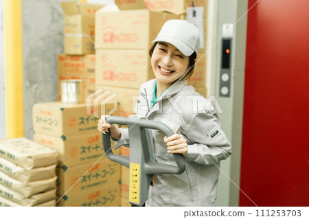 A female worker moves inventory using a jack A female worker moves inventory using a jack 111253703