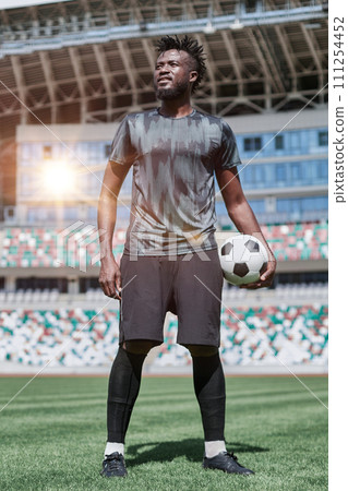confident black football player holding the ball in his hand at the stadium confident black football player holding the ball in his hand at the stadium 111254452