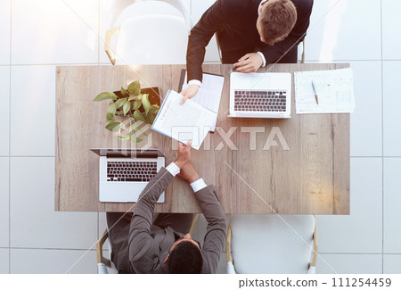Two successful smiling businessmen are working on a laptop. view from above Two successful smiling businessmen are working on a laptop. view from above 111254459