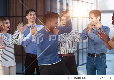 Overjoyed diverse businesspeople triumph have fun dancing in modern office corridor, 111254485