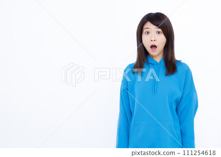 A woman in her 40s wearing a blue hoodie looking surprised 111254618